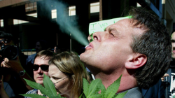 Cannabis crusader Marc Emery, of Vancouver, smokes marijuana as he holds a plant at a gathering of pro-marijuana legalization supporters outside police headquarters in Toronto.